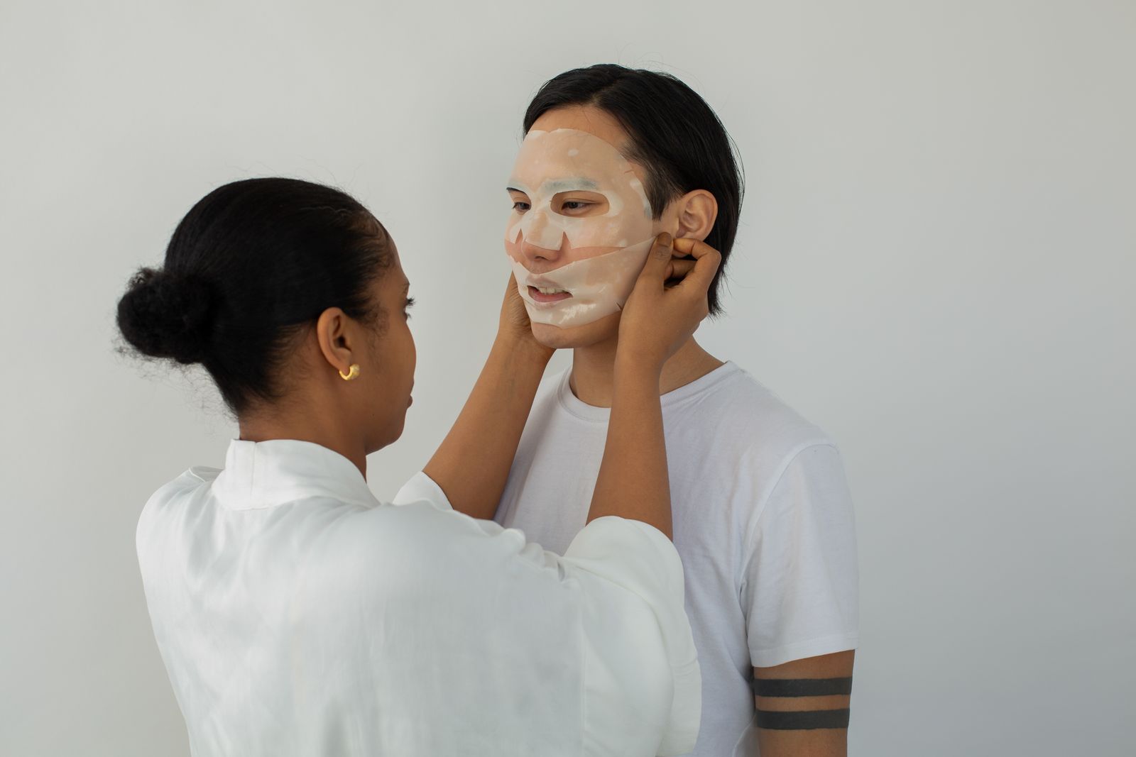 A Black esthetician applying a moisturizing mask during a facial