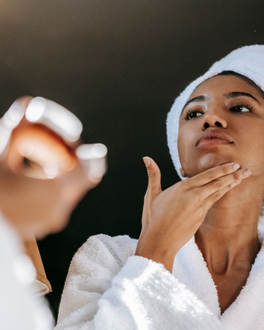 Woman in a white robe and towel caring for her skin