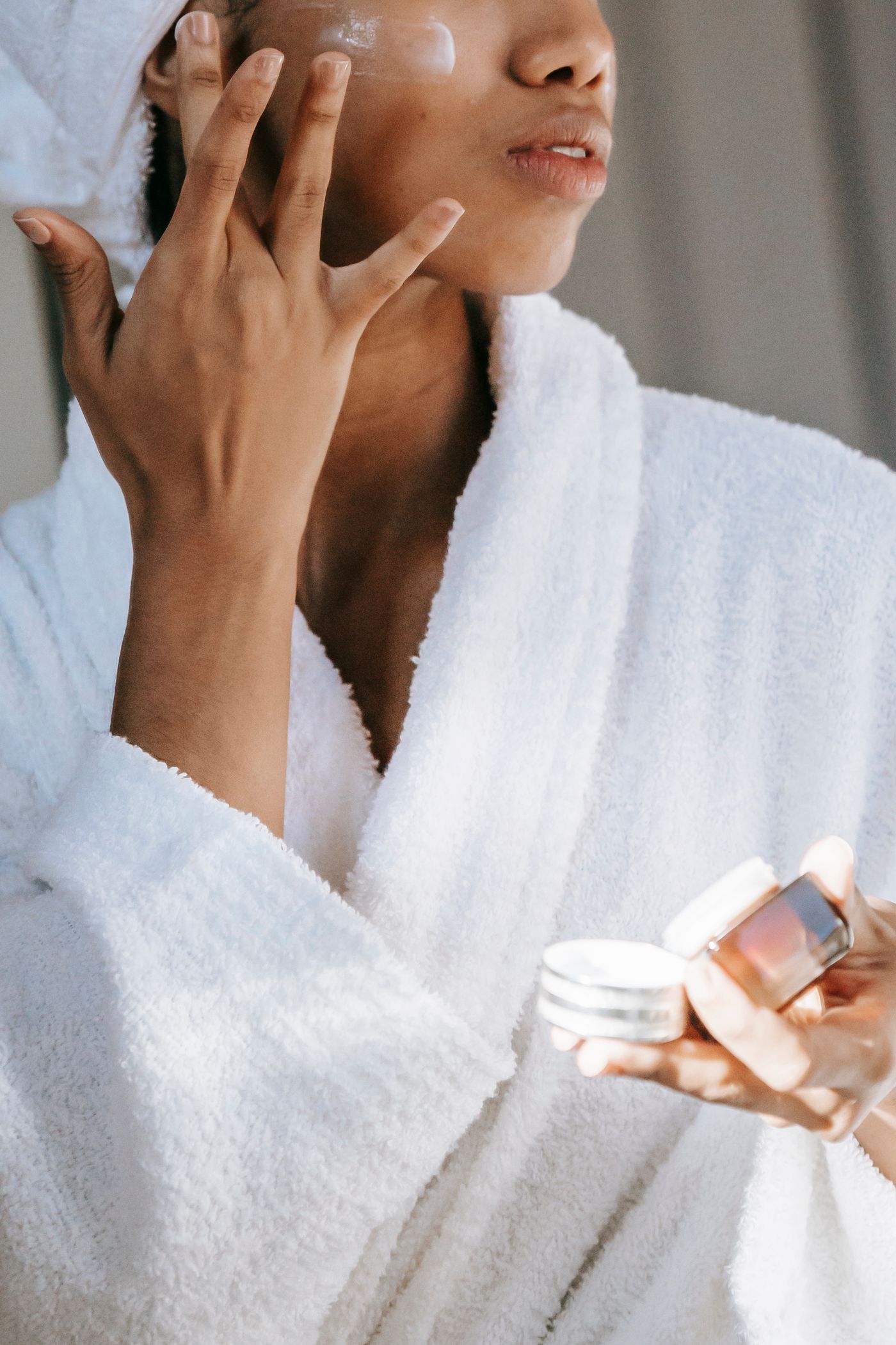 Woman in a robe applying skincare cream